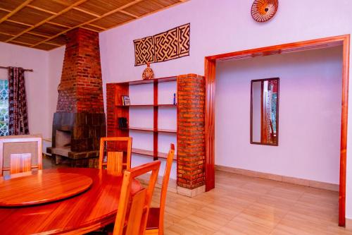 a dining room with a table and a clock on the wall at Isange Paradise Resort in Ruhengeri