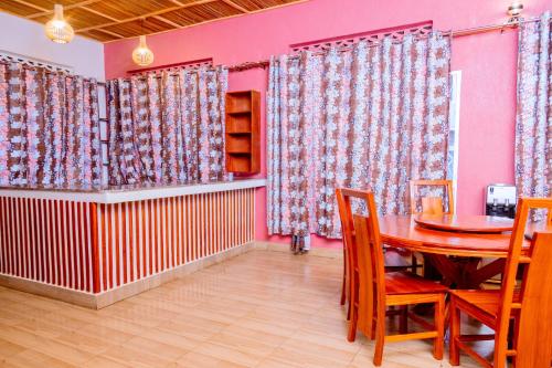 a dining room with a table and chairs and pink walls at Isange Paradise Resort in Ruhengeri