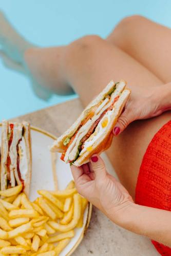 a woman holding a sandwich and a plate of fries at Radisson Blu Hotel Nice in Nice