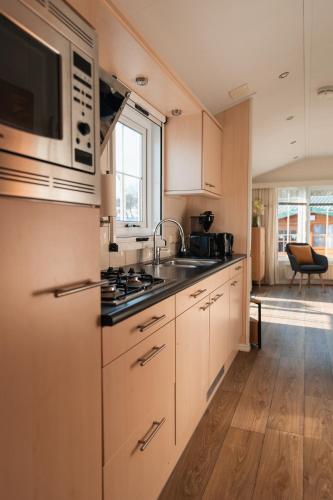 a kitchen with a sink and a microwave at Chalet aan de bosrand in De Koog