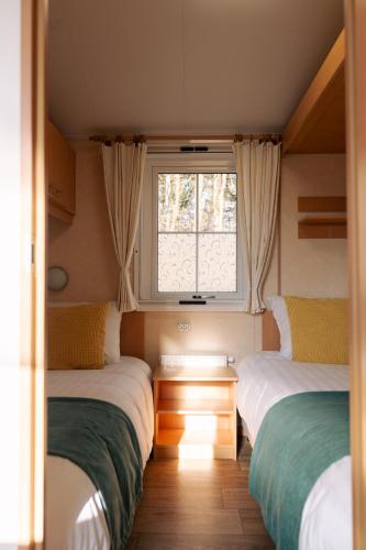two beds in a small room with a window at Chalet aan de bosrand in De Koog