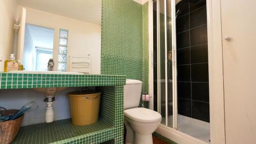 La salle de bains est pourvue de carrelage vert, de toilettes et d'un lavabo. dans l'établissement 11 Chic sunny flat at montorgeuil, à Paris