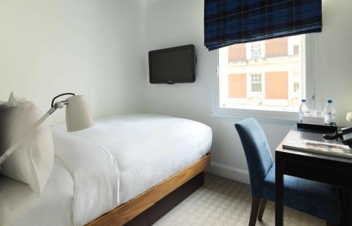 a bedroom with a bed and a desk and a tv at Radisson Blu Hotel, London Tottenham Court Road in London