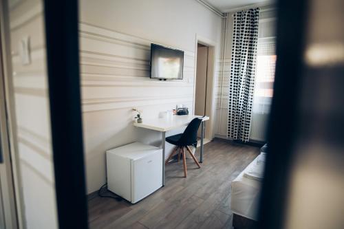 a bathroom with a sink and a desk with a chair at Guest House Family in Kanjiža