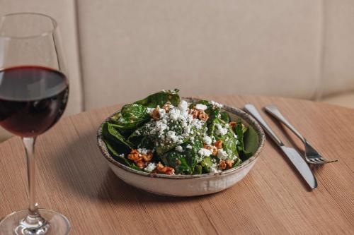 a bowl of salad on a table next to a glass of wine at Radisson Blu Hotel, London Tottenham Court Road in London