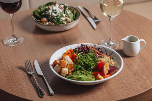 a table with a bowl of salad and wine glasses at Radisson Blu Hotel, London Tottenham Court Road in London