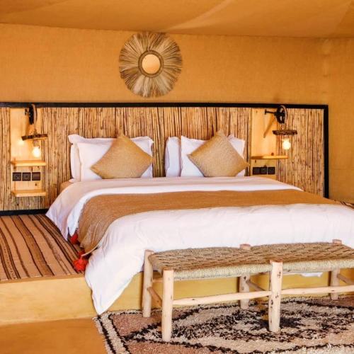 a bedroom with a large bed and a mirror at Kalimba Luxury Desert Camp in Merzouga