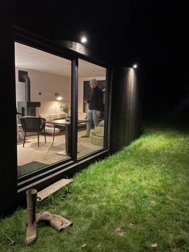 a man standing in a house looking into a yard at Time-Out Cabin in Zottegem