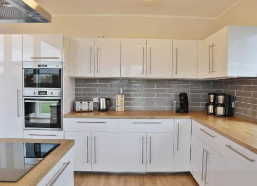 a white kitchen with white cabinets and appliances at NEU Villa Heidetraum, 20 Gaeste, Sauna, Pool in Dorfmark