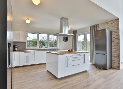 a kitchen with white cabinets and a stainless steel refrigerator at NEU Villa Heidetraum, 20 Gaeste, Sauna, Pool in Dorfmark