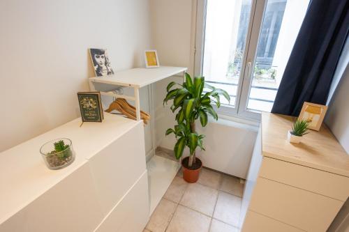 une chambre avec des armoires blanches et une plante en pot dans l'établissement Studio en plein coeur de Paris deuxieme arrondissement Quartier Montergueil Chatelet, à Paris