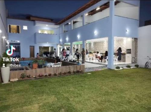 Un gran edificio con césped delante. en Hostel Tia Ró Quartos Feminino e Masculino Lugar de paz, en Governador Valadares