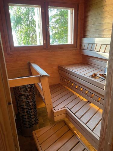 an empty sauna with two benches and two windows at Rantahelmi-huvila in Eurajoki