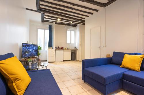un salon avec un canapé bleu et une télévision dans l'établissement Studio en plein coeur de Paris deuxieme arrondissement Quartier Montergueil Chatelet, à Paris