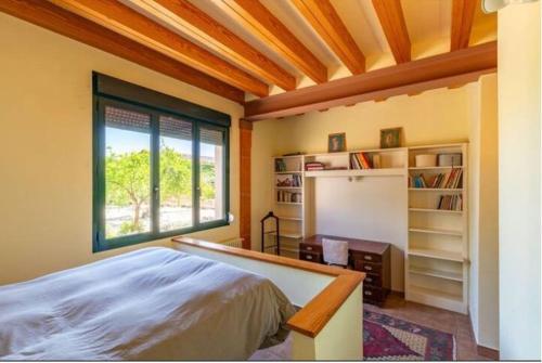 MejoradaにあるLa encina del pastorのベッドと窓と本棚のある寝室
