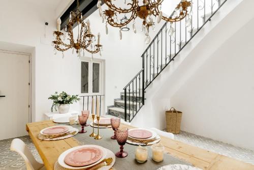 a dining room with a wooden table and chandeliers at Plaza España 5 Casa con encanto, terraza y vistas in Vejer de la Frontera