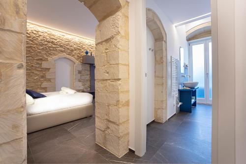 a living room with a couch and a stone wall at Ad Maiora - Design Rooms in Ragusa