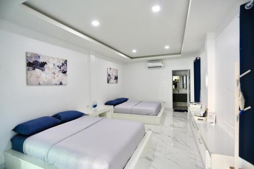a white bedroom with two beds in it at The Munique Cliff House Chumphon - private jacuzzi with beach views in Chumphon
