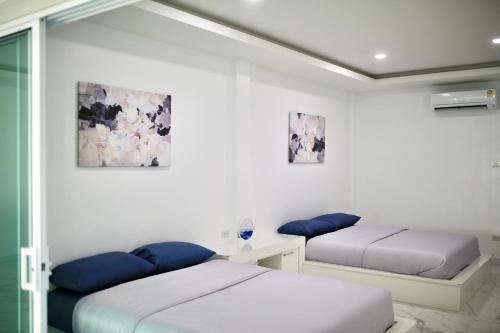 two beds in a room with white walls at The Munique Cliff House Chumphon - private jacuzzi with beach views in Chumphon