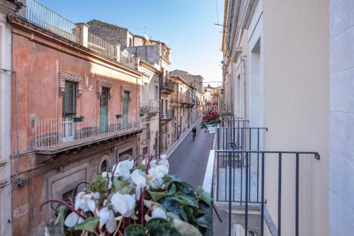 a street with buildings and a plant on a balcony at Ad Maiora - Design Rooms in Ragusa