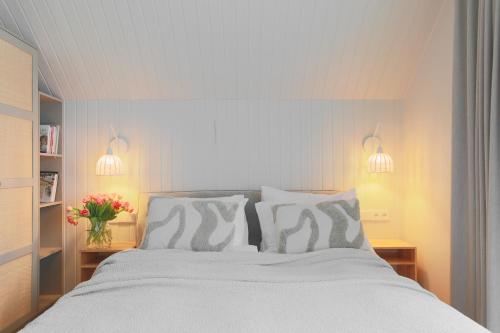 a bedroom with a white bed with pillows and flowers at Vila 44 in Druskininkai