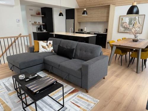 a living room with a couch and a table and a kitchen at BLOOM - Luxe et Confort en forêt in Valcartier Station