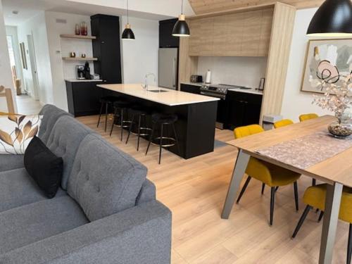 a living room and kitchen with a couch and a table at BLOOM - Luxe et Confort en forêt in Valcartier Station