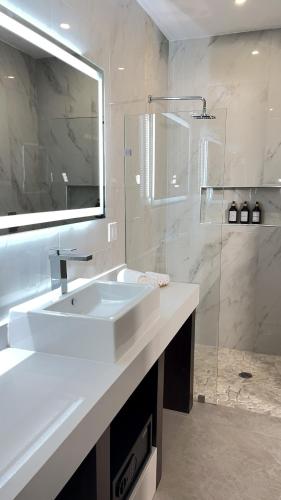 a white bathroom with a sink and a shower at Hotel Loreto Palmar in Loreto