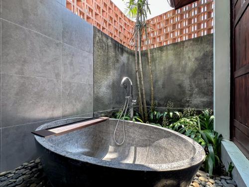 a bath tub in a bathroom with plants at Kawul Harvest Palace Tanah Lot in Tanah Lot