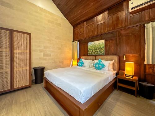 a bedroom with a bed with blue pillows on it at Kawul Harvest Palace Tanah Lot in Tanah Lot