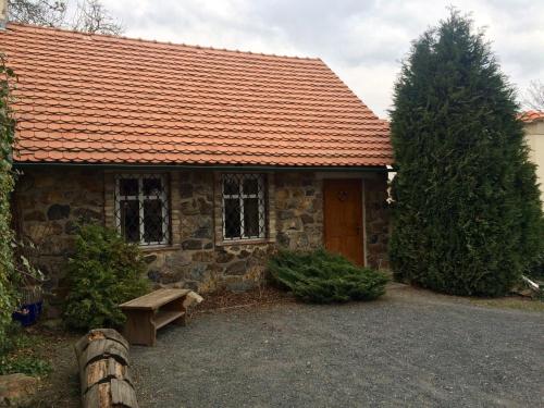 a stone house with a red roof and a bench at Penzion V polích in Malé Číčovice