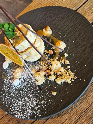 a black plate with a dessert on a table at ALMMONTE PRÄCLARUM SUITES Design Hotel in Wagrain