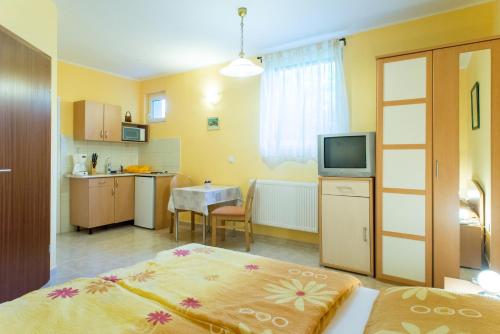 バラトンギュルクにあるAndrea Apartmanházのベッド1台、キッチン(テレビ付)が備わる客室です。