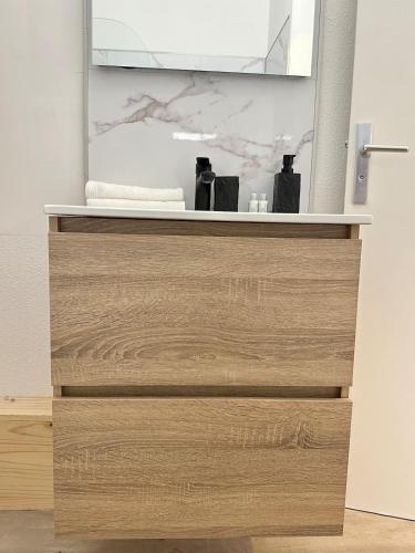 La salle de bains est pourvue d'une commode en bois avec un miroir. dans l'établissement Studio MBS 1 - Cosy, Tram, Wifi, Parking, Equipé, à Montpellier