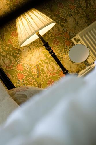 a lamp and a mirror on a wall at Burnside B&B in Keswick