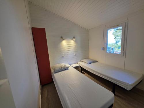 deux lits dans une petite pièce avec une fenêtre dans l'établissement Chalet 4-6 personnes, à Agde