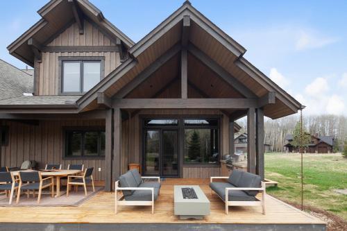 a house with a wooden deck with chairs and a table at Lodge at Whitefish Lake in Whitefish