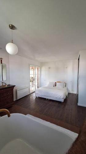 a white bedroom with a bed and a window at La Villa verdoyante in Baillargues