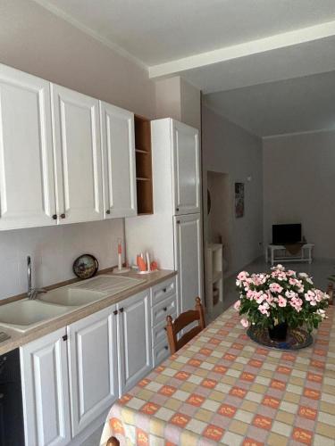 a kitchen with white cabinets and a table with flowers on it at Duomo Girgenti Loft in Agrigento