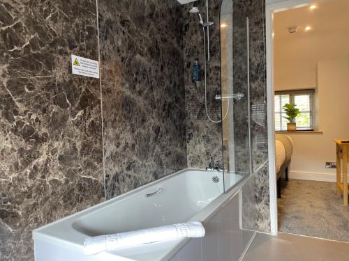 a bathroom with a bath tub and a shower at Prince Llewelyn Hotel in Beddgelert