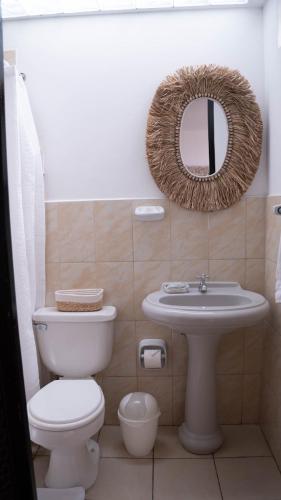 a bathroom with a toilet and a sink and a mirror at Hostal Brisas del Mar in Punta Negra