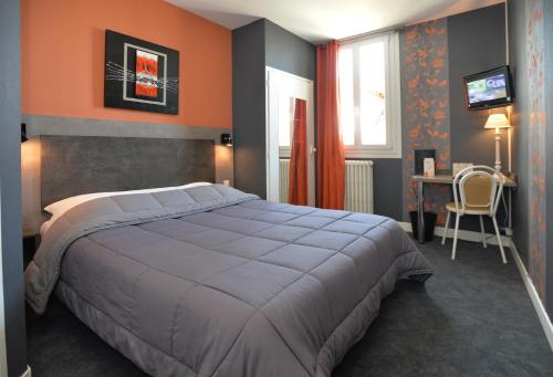 a bedroom with a bed and a desk and a window at Hôtel La Croix Blanche in Tarbes