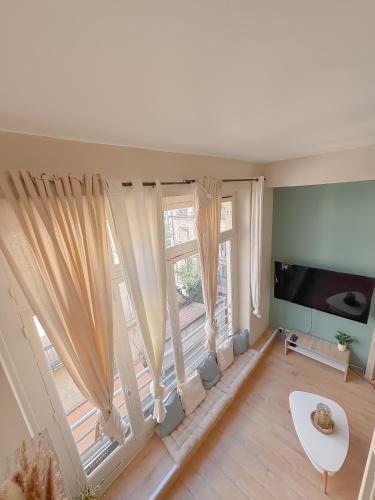 - un salon avec une grande fenêtre et des rideaux dans l'établissement L'Écrin de la Comédie, à Montpellier