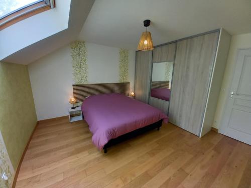 a bedroom with a purple bed and a mirror at Gîte, Maison de campagne in Maizières