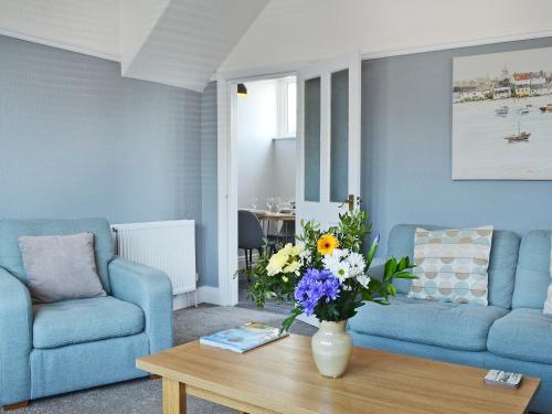 una sala de estar con 2 sofás azules y una mesa con flores en The Beach House, en Saint Annes on the Sea