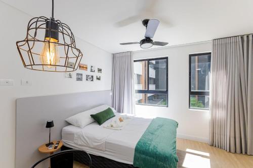 Un dormitorio con una cama y una lámpara de araña en Rise Urban Habitat - Água Verde | Gonzaga Stays, en Curitiba
