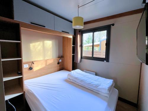 Un dormitorio pequeño con una cama y una ventana. en Le Ti Bois, Chalet tout équipé vue forêt, 5 prs, en La Teste-de-Buch