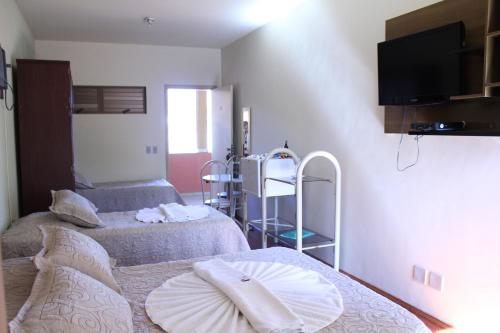 a room with two beds and a tv on the wall at Café Palace Hotel in Três Pontas