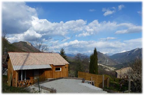 a small wooden house with mountains in the background at chalet Le Géranium in Briançonnet