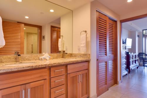 a bathroom with two sinks and a large mirror at Lahaina Condo with Patio, Ocean Views and Pool Access! in Kahana